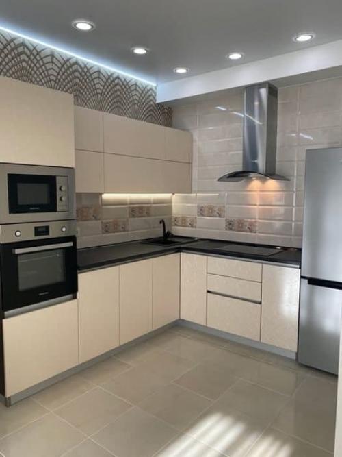 Объединенное пространство кухни - гостиной со столовой зоной в бежевых тонах с золотистыми элементами.