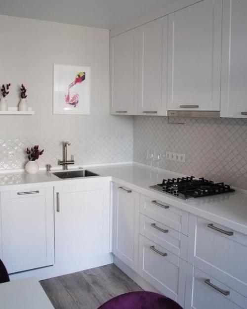 Меблировка обеденной зоны яркими цветными стульями в белом интерьере кухни. 01